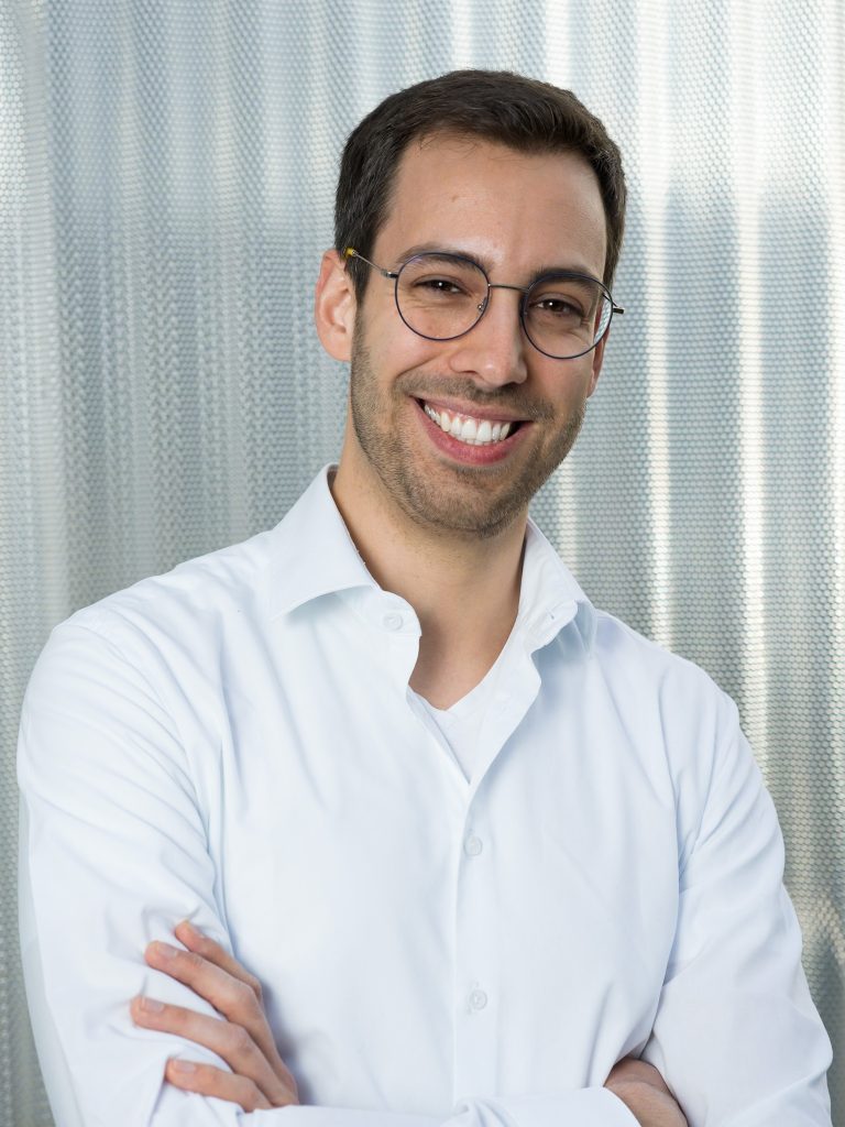 Lachender Mann im Portrait mit Brille und weißem Pullover